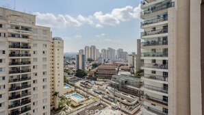 A high-rise residential building with multiple balconies, a swimming pool, and a view of the cityscape. - Apt in SP 600m From Allianz Parque - Tro0154 (São Paulo)
