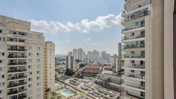A high-rise residential building with multiple balconies, a swimming pool, and a view of the cityscape.