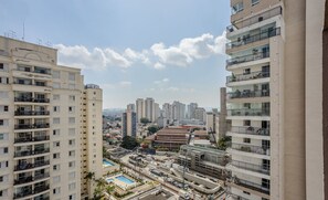 Un edificio residencial alto con varios balcones, una piscina y vistas de la ciudad.
