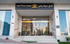 The entrance to Saif Plus Hotel with a sign in both English and Arabic, a glass door, and a set of stairs leading up to the entrance. - Saif Plus 1 (Makkah)