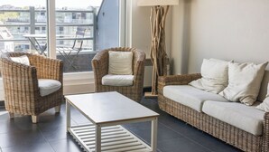 Una sala moderna con muebles de mimbre, una mesa blanca y un sofá con cojines.