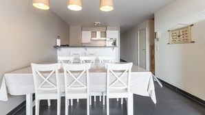 Un comedor con una mesa para cuatro, sillas blancas y lámparas colgantes.