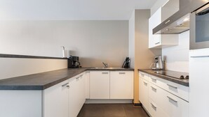 Una cocina moderna con armarios blancos, encimera oscura y electrodomésticos de acero inoxidable.