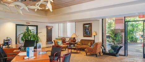 A lobby with a reception desk, seating area, and a large window with a view of the outdoors.