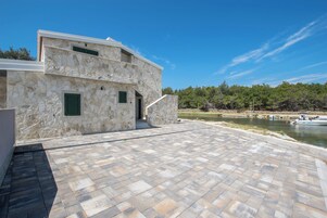 Un bâtiment en pierre doté d’un patio dallé et offrant une vue sur une rivière.