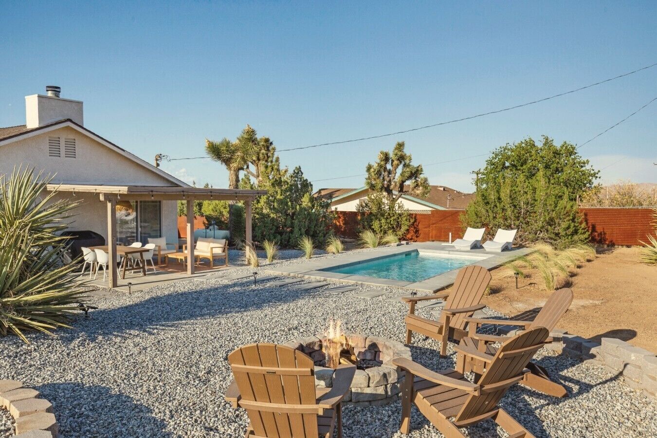A residential backyard with a swimming pool, outdoor seating area, and a covered patio.