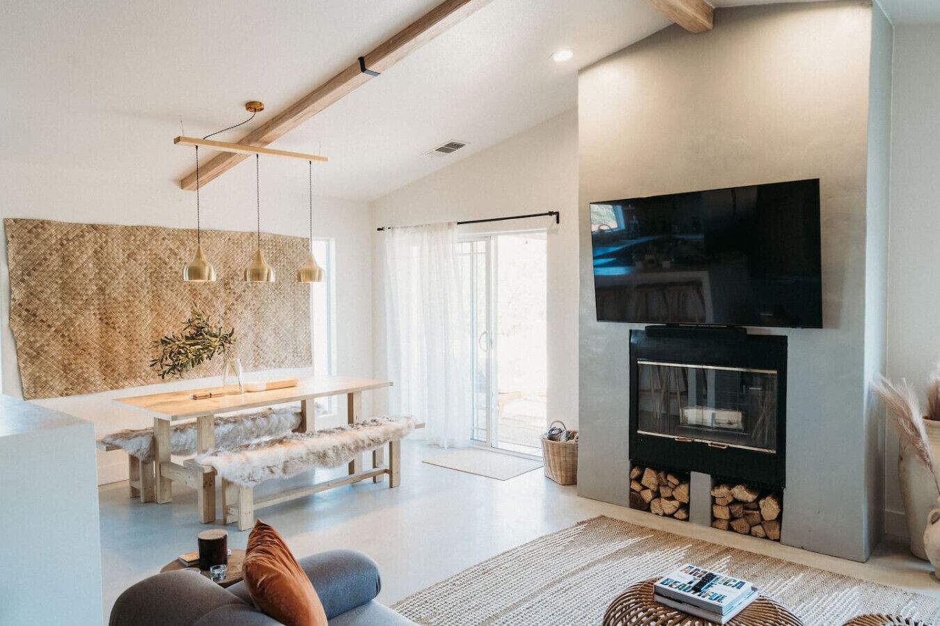 A modern living room with a fireplace, a dining area, and a TV mounted on the wall.