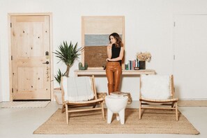 A room with a wooden door, a desk with a plant, two chairs, and a small white table. - License To Chill | Pool + Hot Tub | Enclosed Yard (Yucca Valley)