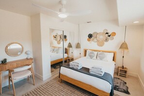 A bedroom with a bed, bedside tables, a desk, and a mirror.