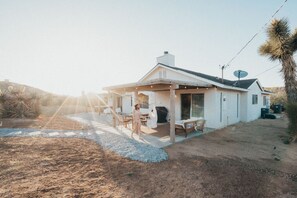 A single-story house with a covered patio, a satellite dish, and a gravel driveway.