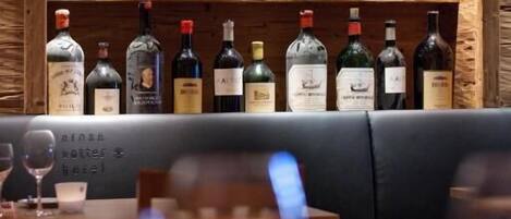 A bar area with a wooden shelf displaying various bottles of alcohol.