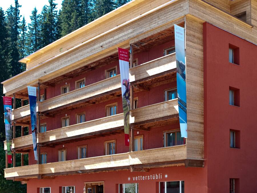 Un hotel de varios pisos con fachada roja y balcones de madera.