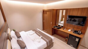 A hotel room with a bed, a desk with a flat-screen TV, a mirror, and a small refrigerator. - Kenanah AlAziziyah (Makkah)