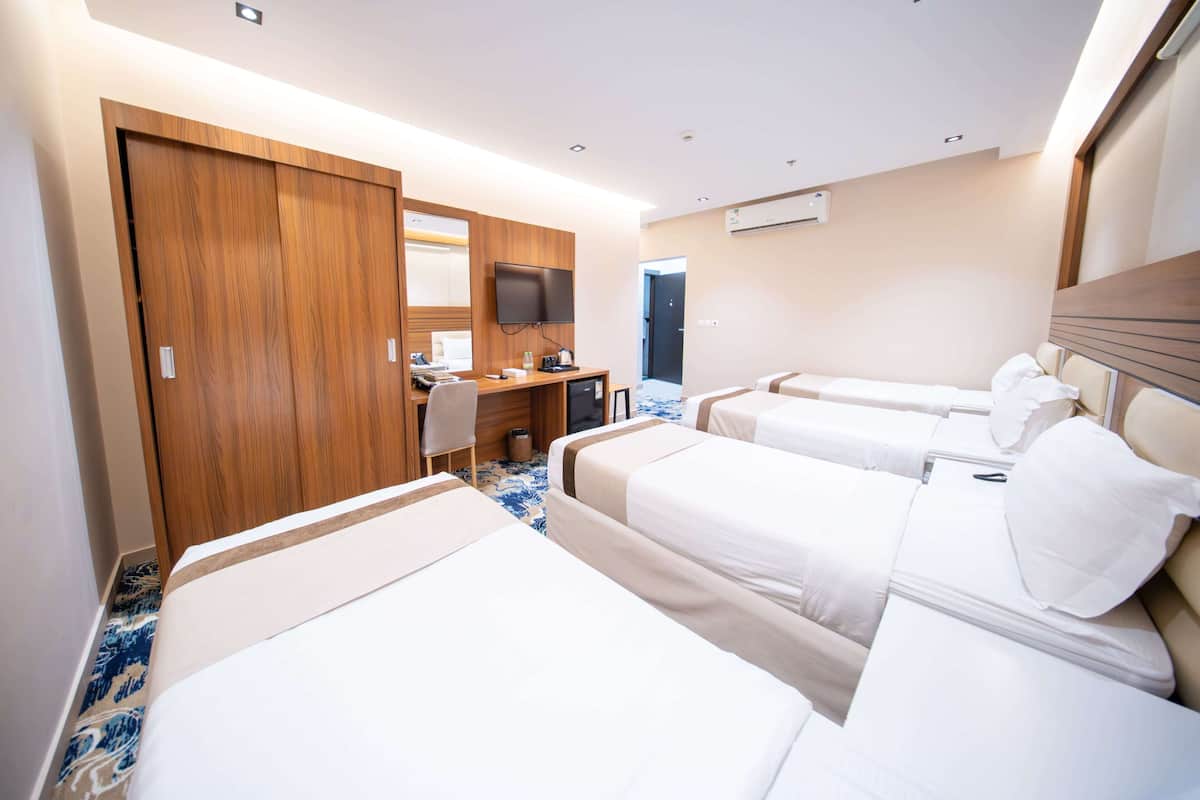 Habitación de hotel con dos camas, un escritorio, un televisor y un armario.