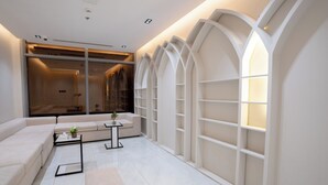 A modern living room with a sectional sofa, a small coffee table, and a bookshelf. - Kenanah AlAziziyah (Makkah)