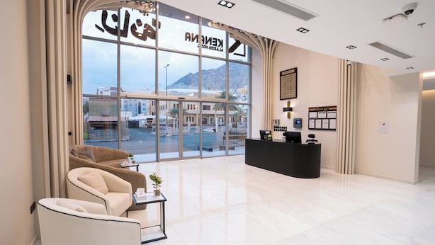 A hotel lobby with a reception desk, seating area, and large windows offering a view of the outside. - Kenanah AlAziziyah (Makkah)