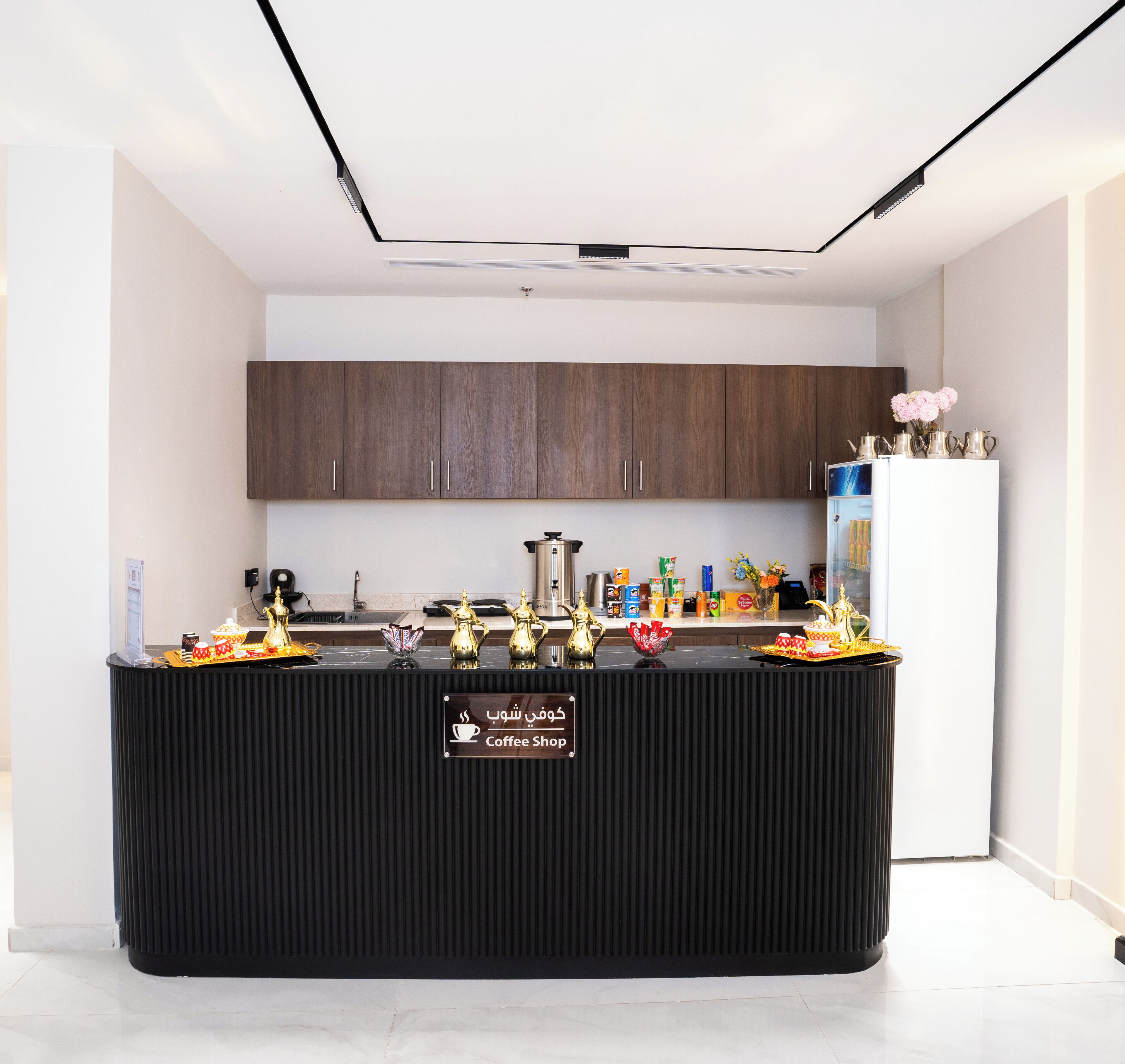 A modern kitchen with dark wooden cabinets, a black countertop, and a coffee shop sign.