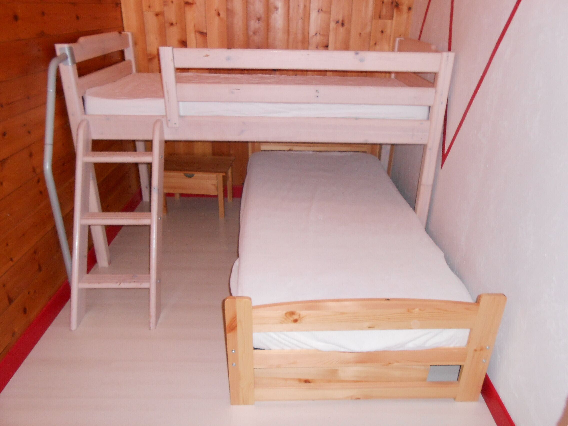 A bunk bed with a ladder and a single bed.