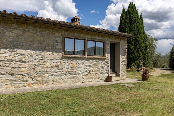 A stone building with a tiled roof, a door, and windows.