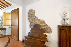 A room with a wooden door, a stone wall, and a cabinet with a glass object on top. - Room 'Rosa I Cipressi' with Shared Garden, Wi-Fi and Air Conditioning (Pontassieve)