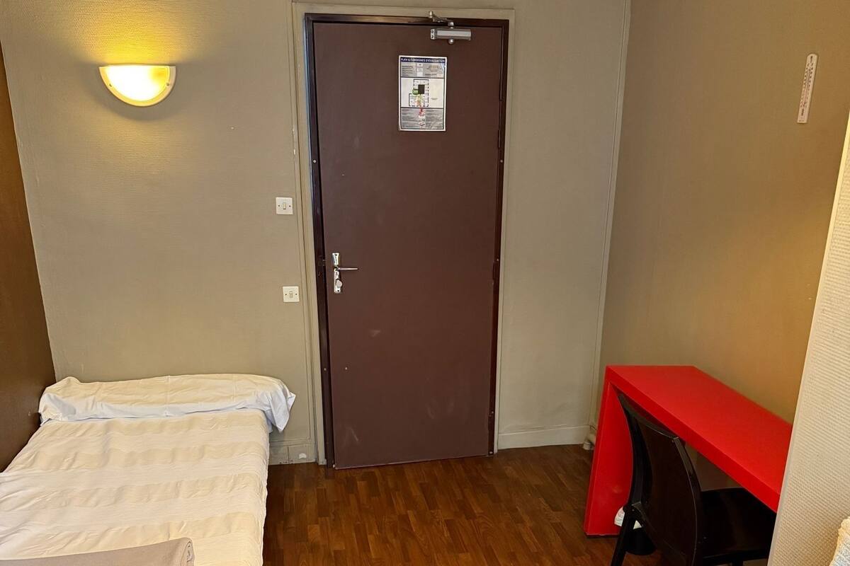 A room with a bed, a desk, and a door.