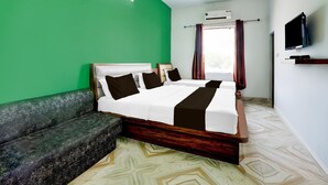 A hotel room with a bed, a sofa, a television, and an air conditioning unit. - Collection O Salasar Balaji Temple Keshav Mahal (Sujangarh)