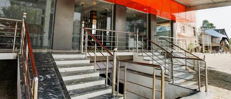 A building with a staircase leading to a covered entrance, a marble floor, and a metal railing.