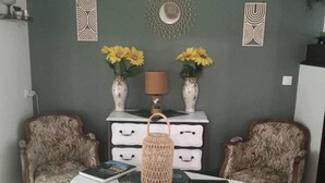A room with a white table, two patterned armchairs, a decorative wall, and a lamp.
