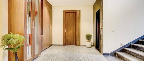 A hallway with patterned flooring, wooden doors, and a staircase.