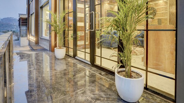 A modern hotel entrance with large glass doors, potted plants, and a reflective marble floor. - Alaya Stays Serene Woods Hotel Near Mall Road (Kasauli)