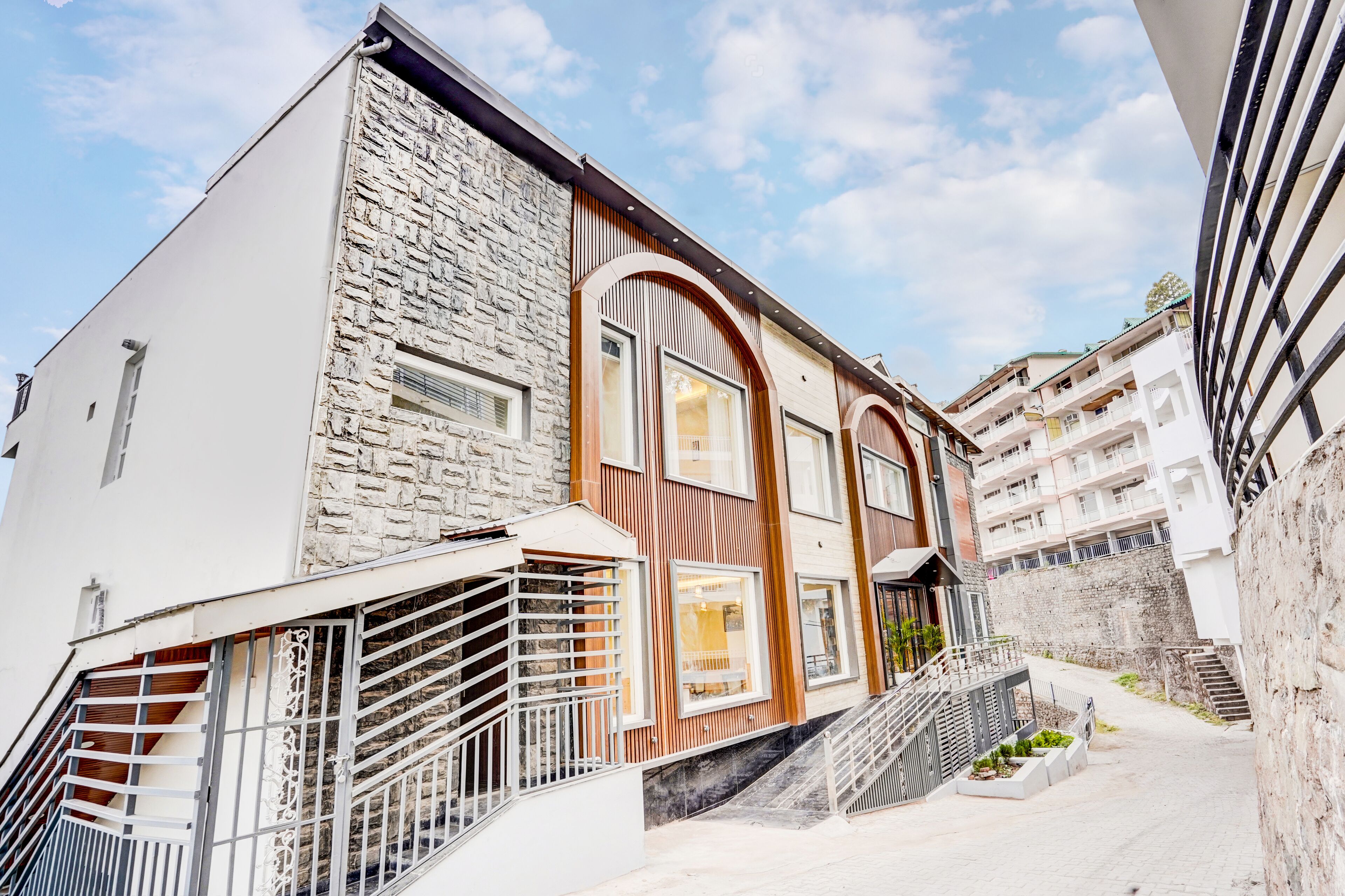 Un bâtiment moderne avec une façade en pierre, de grandes fenêtres et un escalier menant à l’entrée.