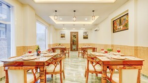 A hotel dining area with wooden tables and chairs, a marble floor, and a view of the outside. - Alaya Stays Serene Woods Hotel Near Mall Road (Kasauli)