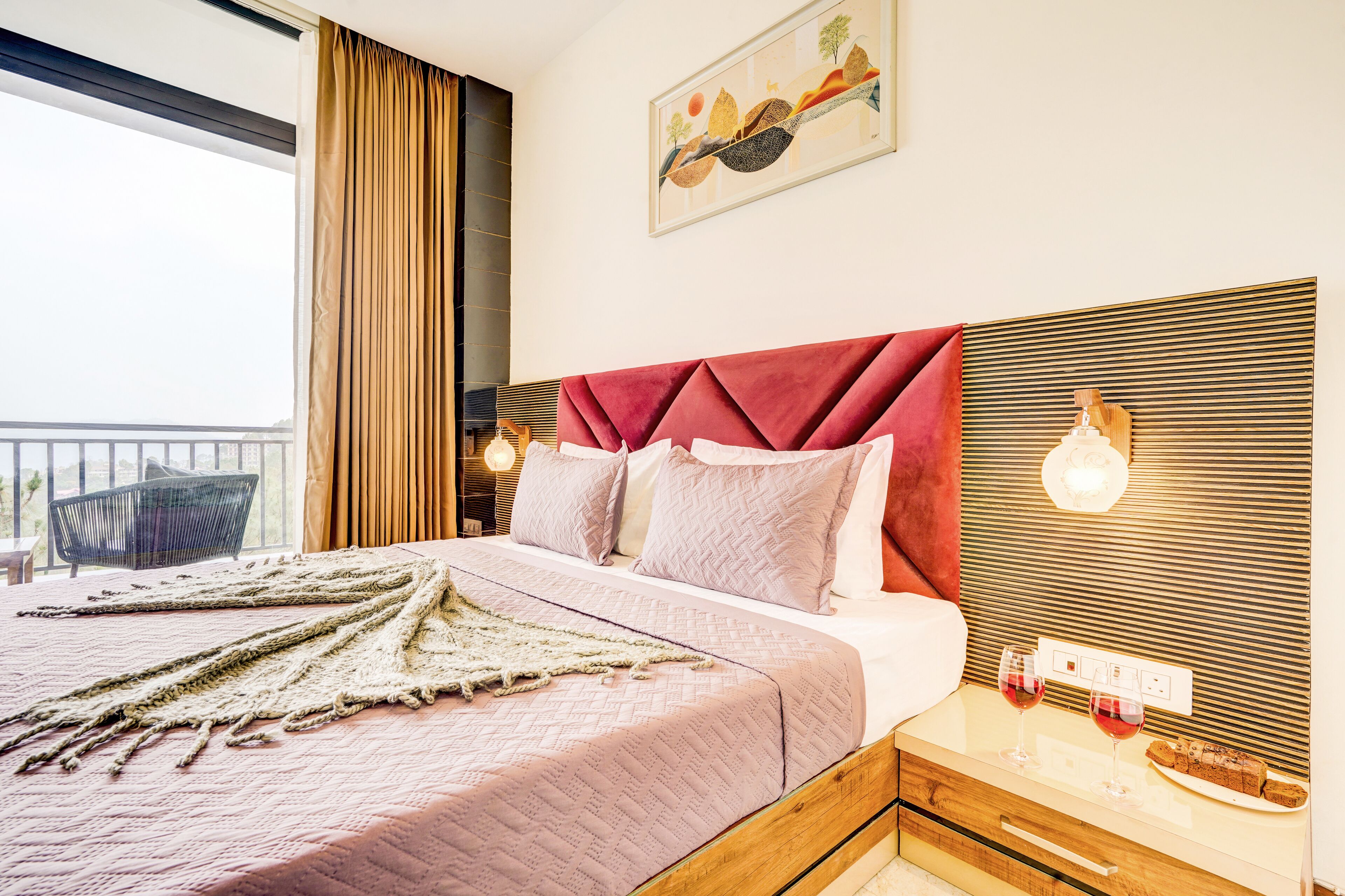 A hotel room with a large bed, a wooden nightstand, a wall-mounted light, and a view of the outdoors.