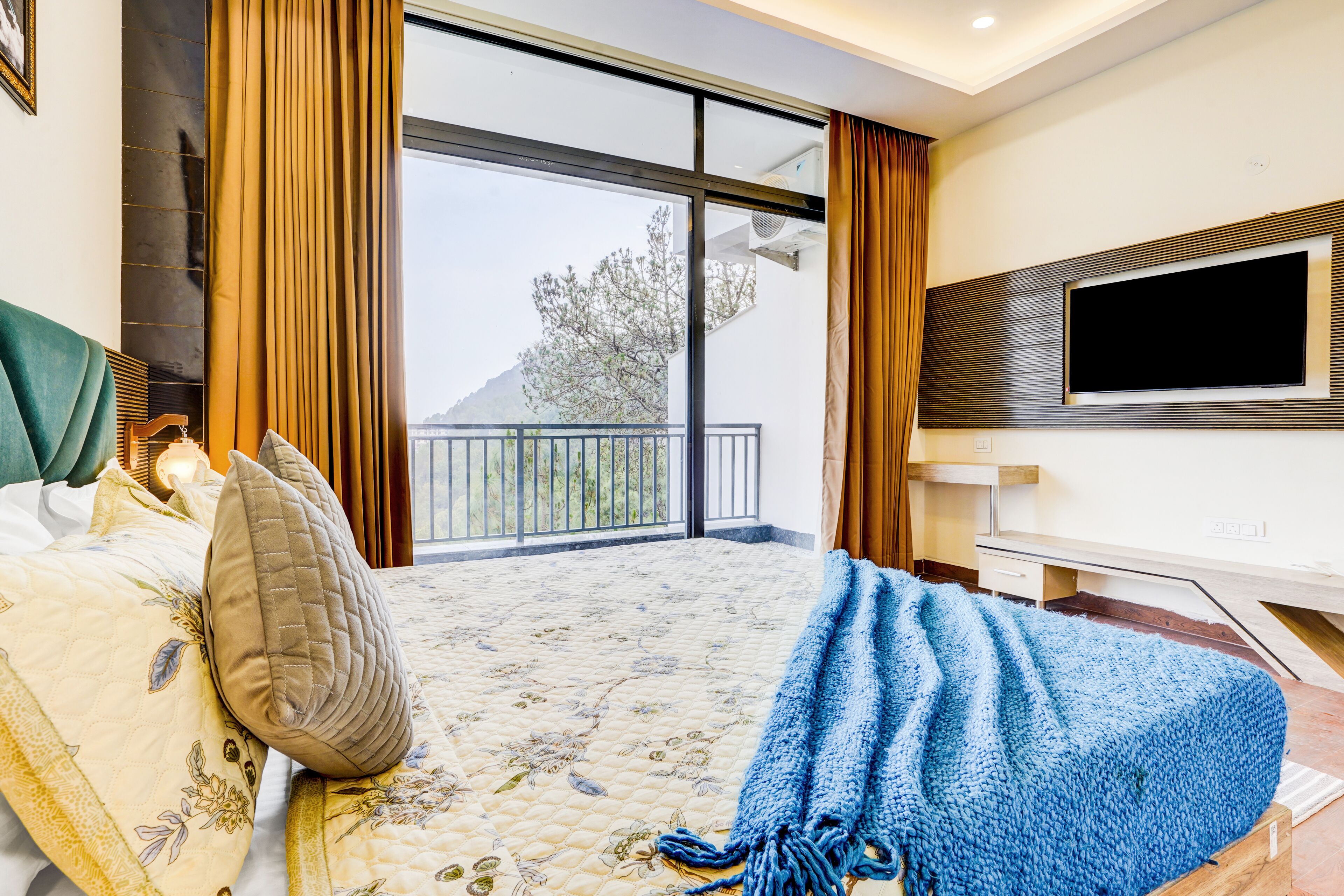 Een hotelkamer met een bed, een televisie, een balkon en uitzicht op de omgeving.