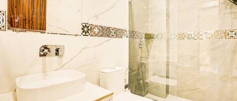 A bathroom with a marble sink, a toilet, and a glass shower enclosure.