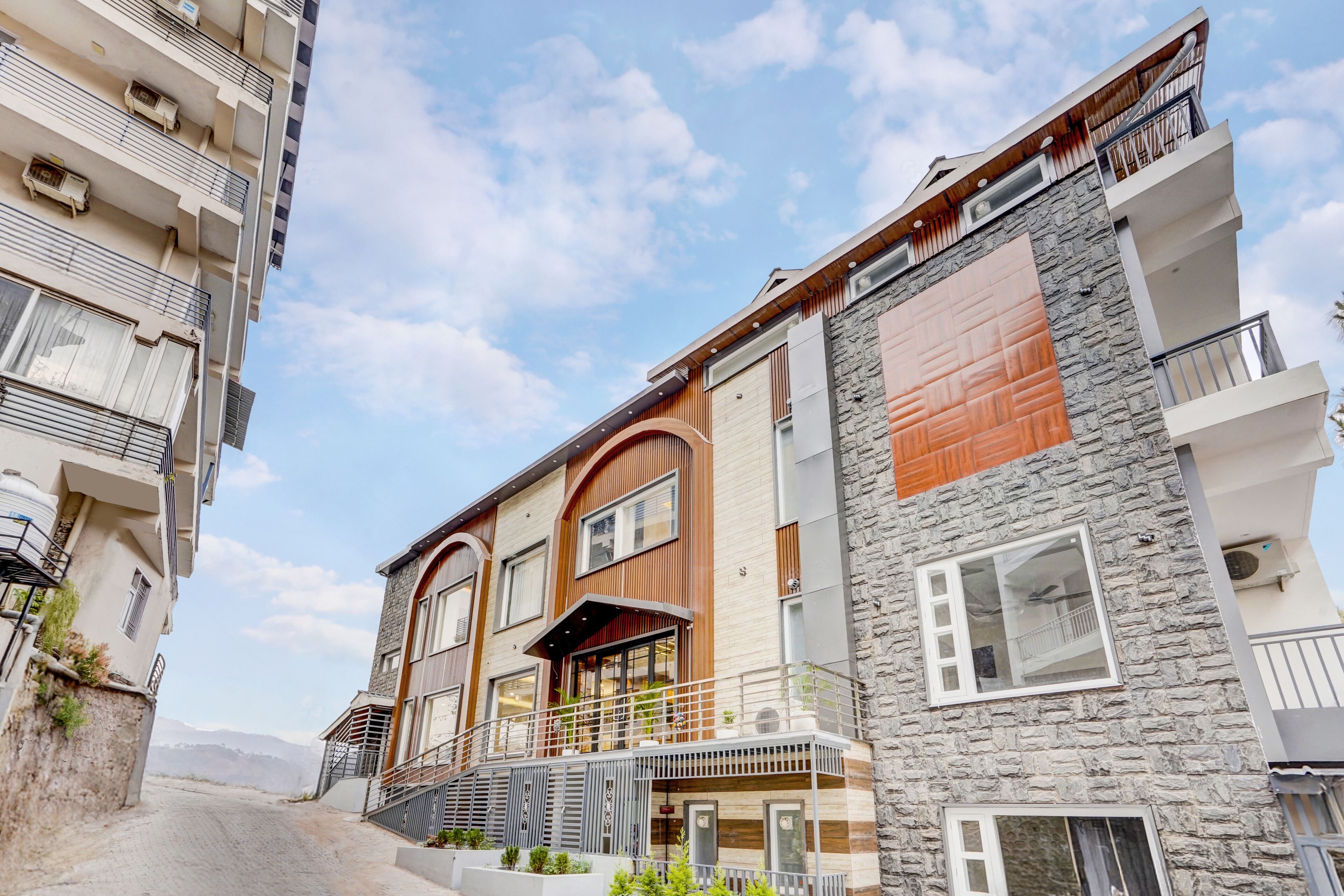 Un edificio residencial de varios pisos con balcones, fachada de piedra y cielo despejado.