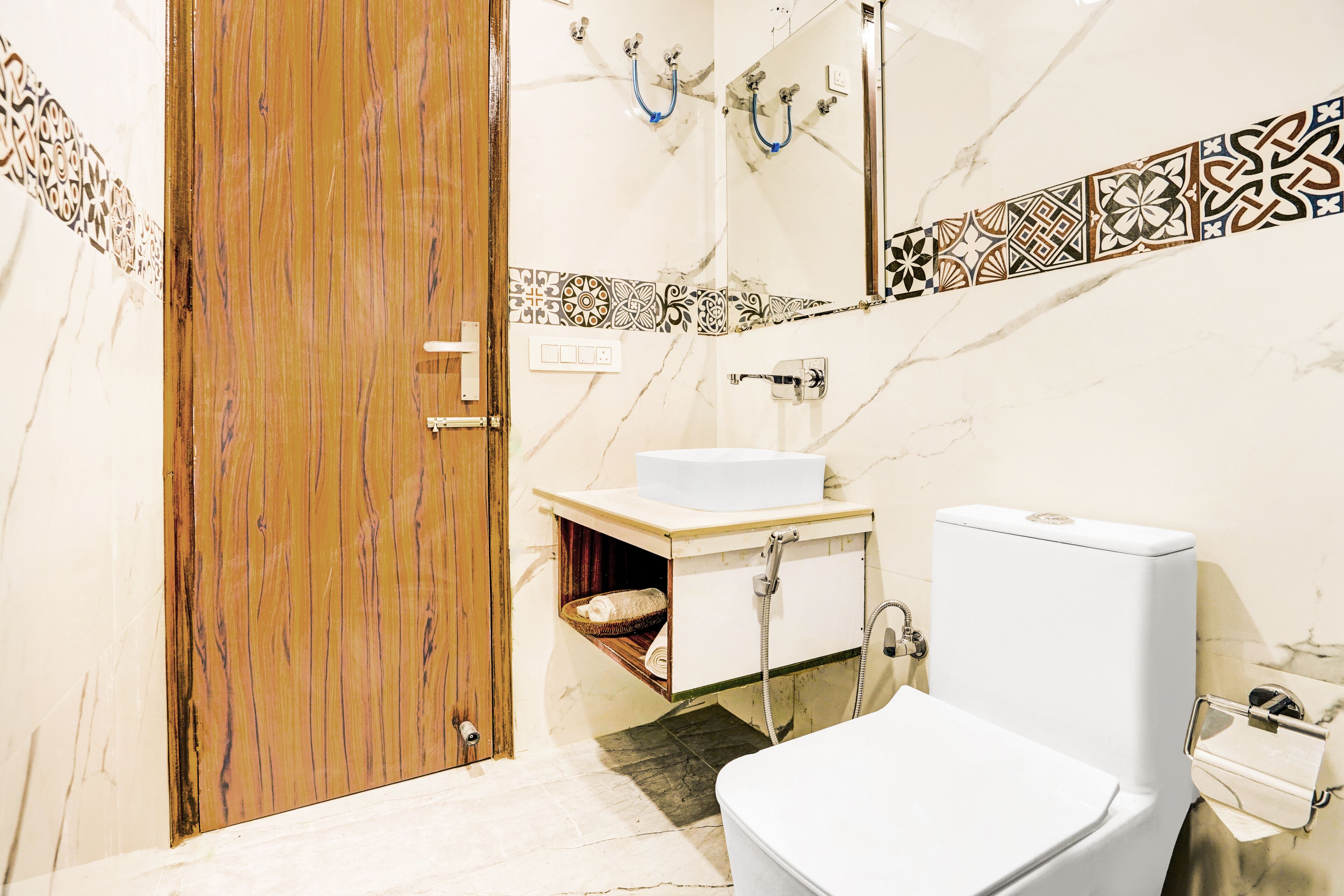 A bathroom with a wooden door, a white sink, a toilet, and a shower area.