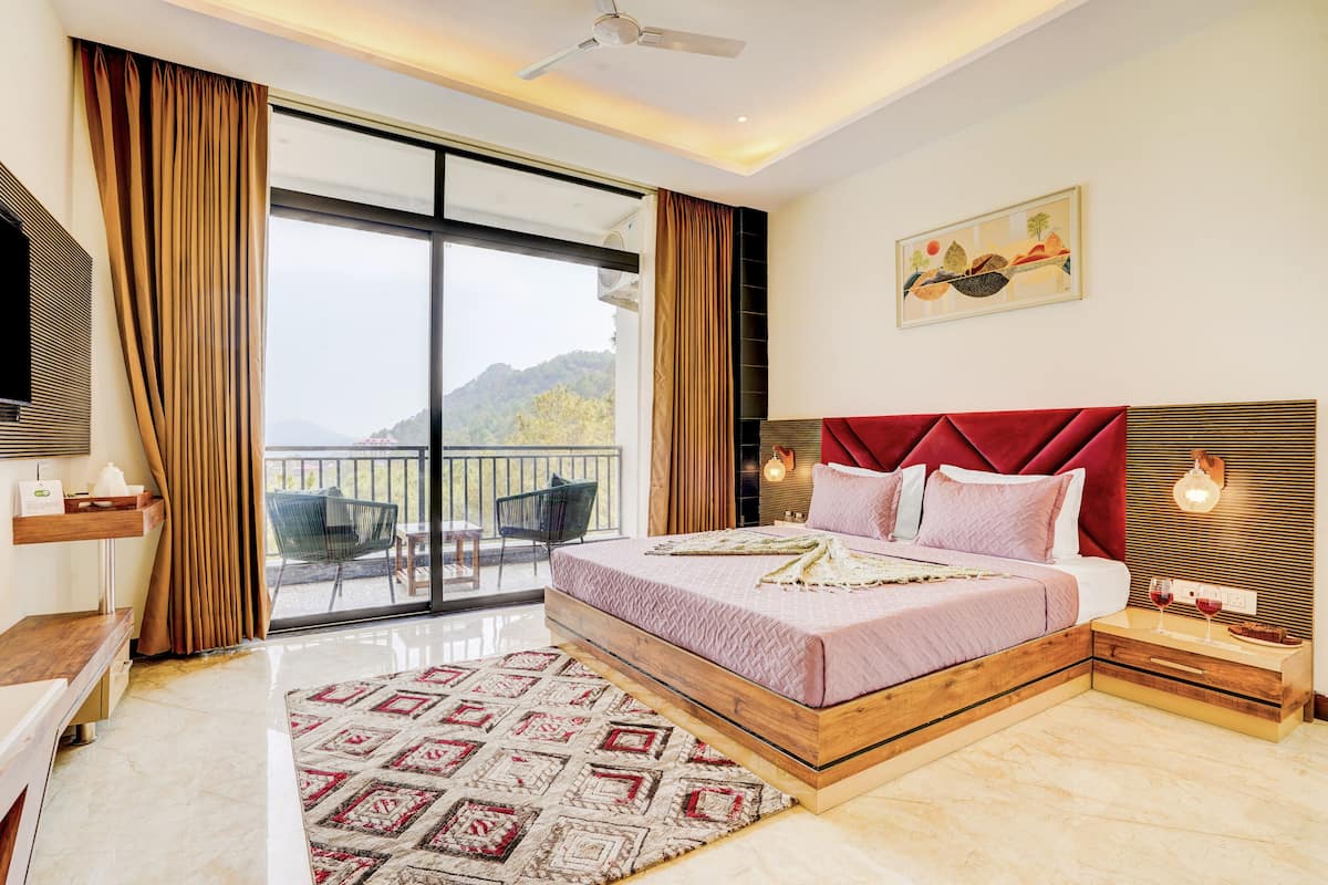 A modern bedroom with a large bed, a balcony with a view, and a painting on the wall.