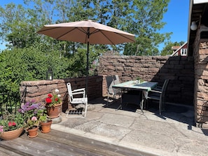 An outdoor patio with a table and chairs, surrounded by stone walls and potted plants.