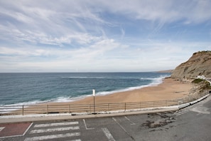 Une route côtière bordée d’une plage et de falaises.