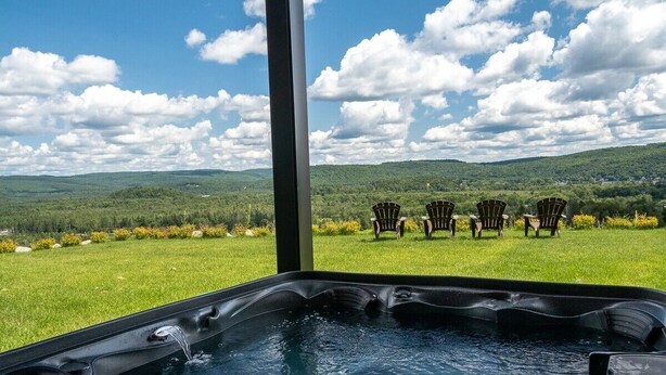 Ein Whirlpool mit Blick auf eine Rasenfläche und Stühle.