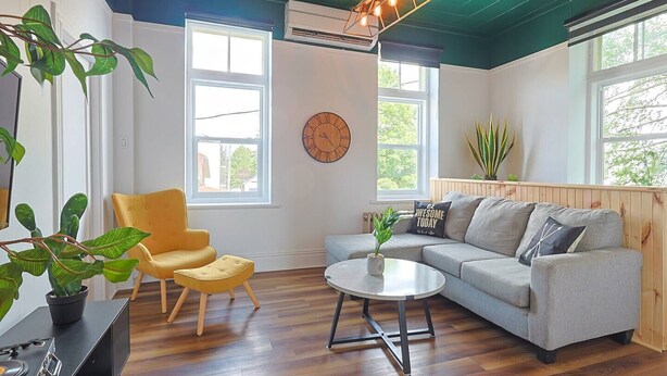 A living room with a sofa, armchair, coffee table, and a clock on the wall.
