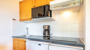 A compact kitchen with wooden cabinets, a microwave, a coffee maker, and a dishwasher.