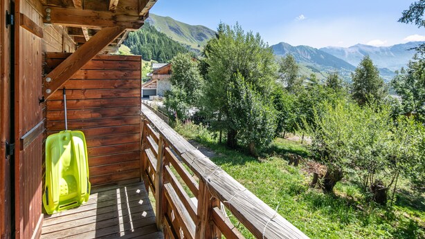 A wooden balcony with a view of a mountainous landscape.