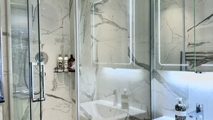 A modern bathroom with a glass-enclosed shower, a large mirror, and a white sink. - Cozy Notting Hill 1 Bedroom - Prime Spot (London)