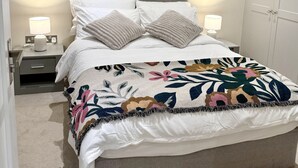 A bedroom with a bed, two nightstands, a grey headboard, and three framed pictures on the wall. - Cozy Notting Hill 1 Bedroom - Prime Spot (London)