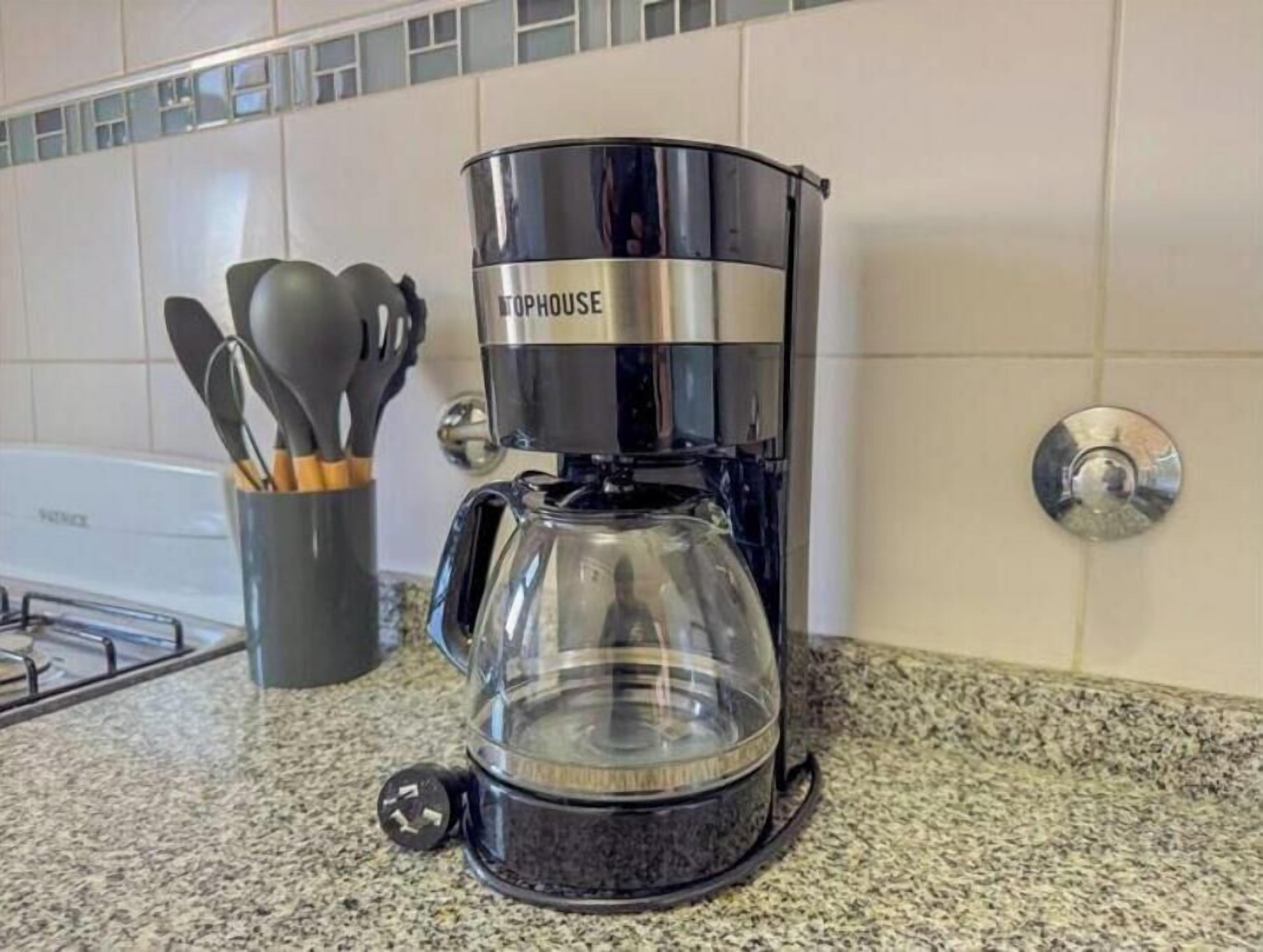 A coffee maker on a kitchen counter with a utensil holder nearby.