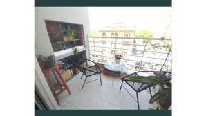 Un balcone con tavolo e sedie, piante in vaso e vista sugli edifici.
