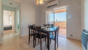 Un espace repas comprenant une table et des chaises, un appareil de climatisation et une vue à travers une porte vitrée.