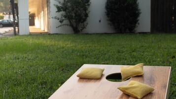 A wooden board with 'The Rockamabe Roadside Inn' text and a logo, placed on grass with two cushions on it.